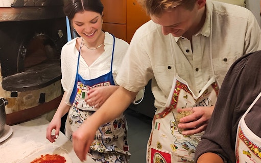 Participants in a pizza-making class in Naples, preparing dough with toppings.