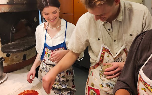 Participants in a pizza-making class in Naples, preparing dough with toppings.