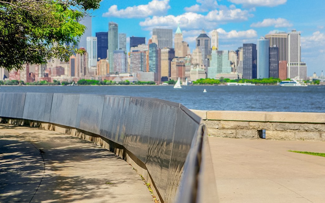 Ellis Island view of Manhattan skyline with ferry on the water.