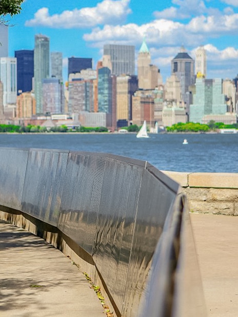 Ellis Island view of Manhattan skyline with ferry on the water.