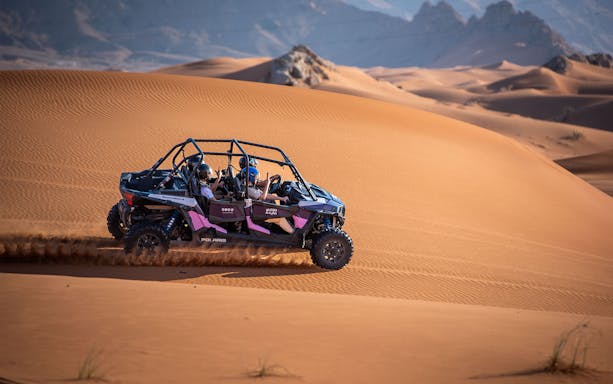 Dune buggy driving through Mleiha desert landscape.