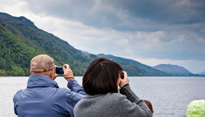 Tourists photographing Loch Ness from a high-speed cruise boat.
