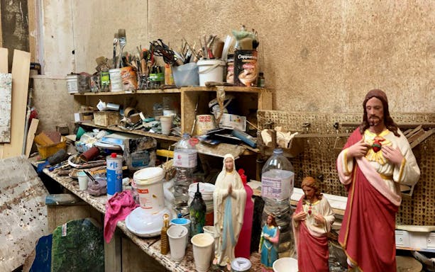 Craft workshop with religious statues and art supplies in Ortigia.