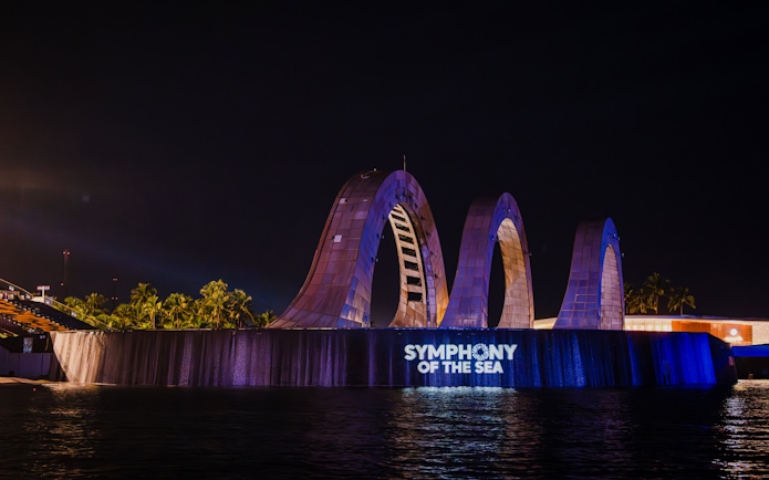 Exterior view of Symphony of the Sea with illuminated arches at night.