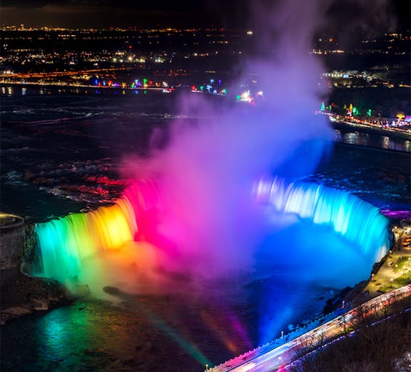 Niagara Falls illuminated in vibrant colors during night light show.