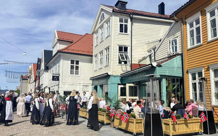People in traditional attire outside a café in Bryggen area, Bergen, Norway.