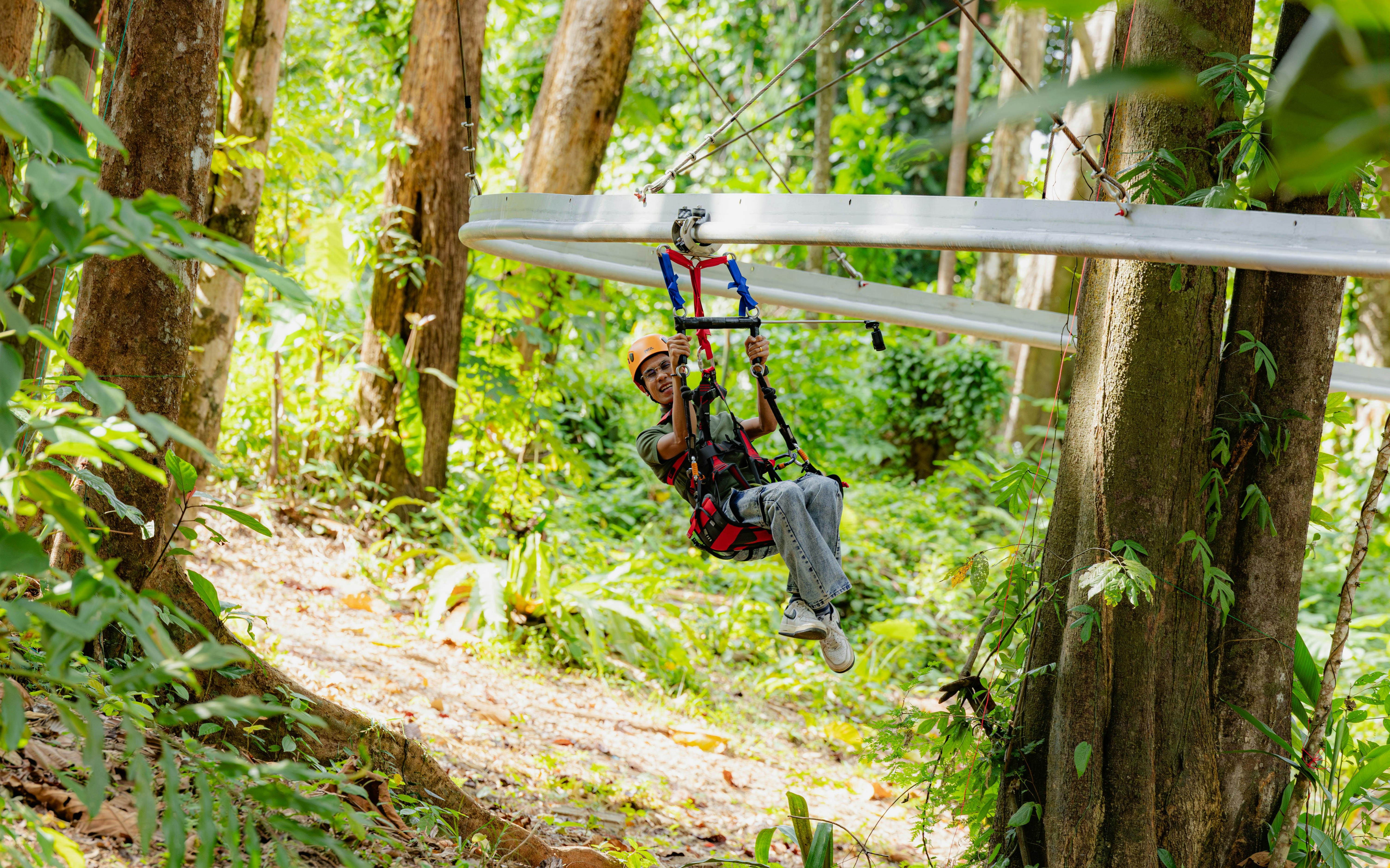 Person ziplining through lush forest at SKY ROCK eco-friendly adventure, Thailand.