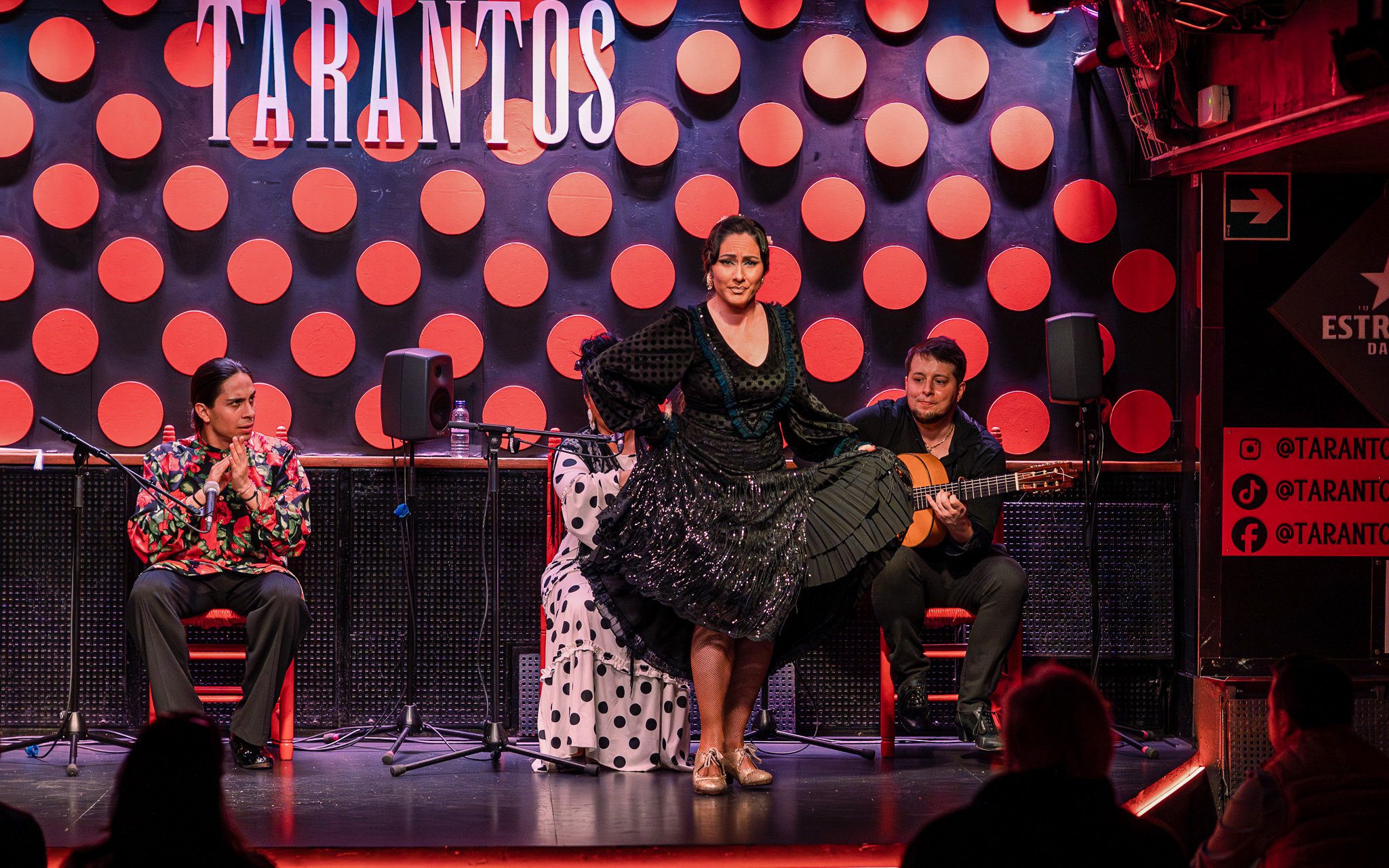 Flamenco dancer performing at Los Tarantos with musicians in Barcelona.