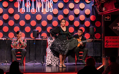Flamenco dancer performing at Los Tarantos with musicians in Barcelona.