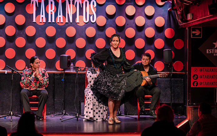 Flamenco dancer performing at Los Tarantos with musicians in Barcelona.