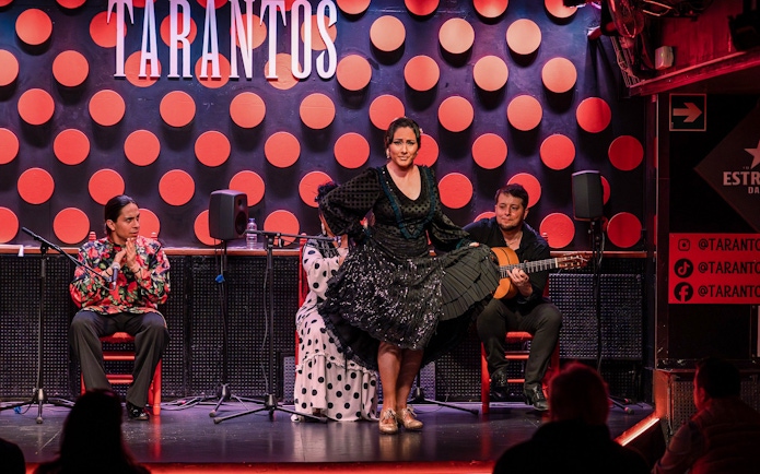 Flamenco dancer performing at Los Tarantos with musicians in Barcelona.