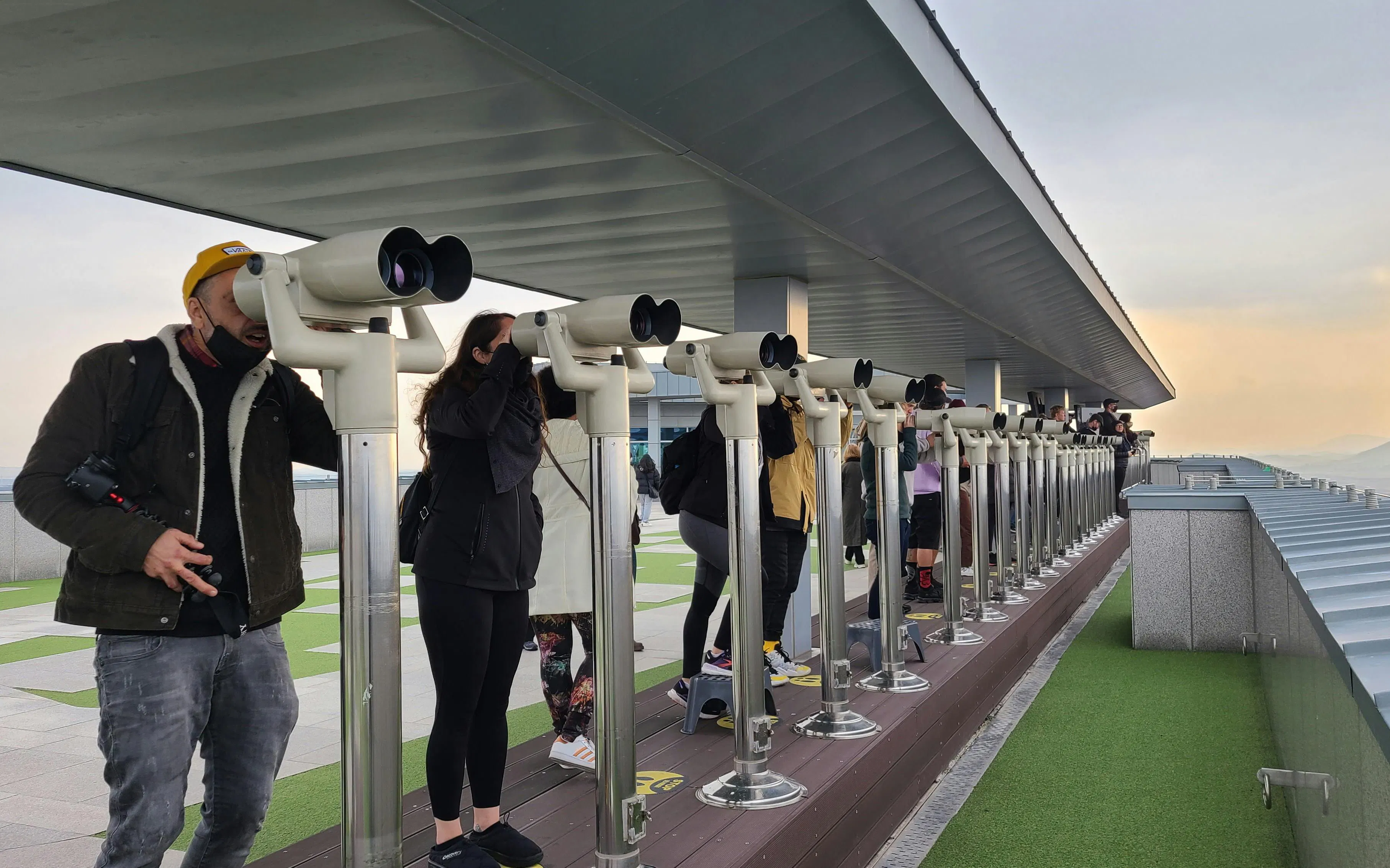 Tourists using binoculars at a DMZ observation deck on the North Korea tour.