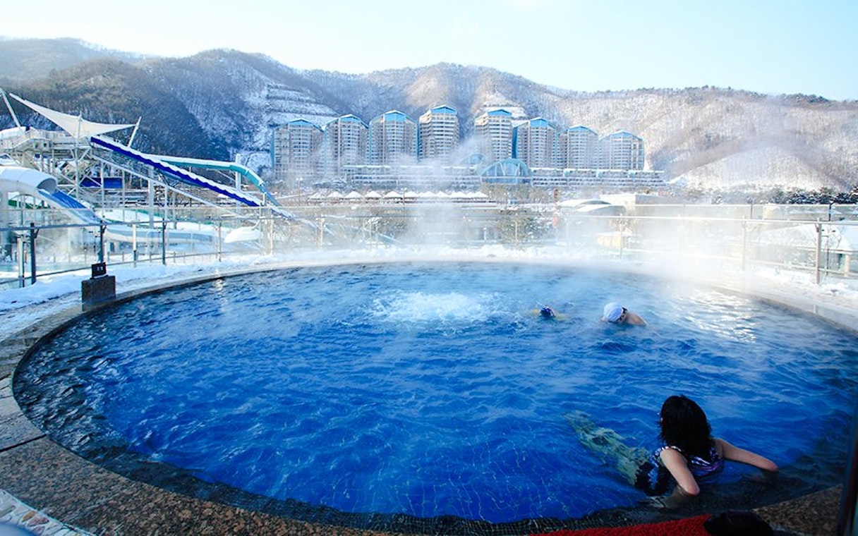 Thermal bath with swimmers at Vivaldi Park Ski World, snowy mountains in the background.