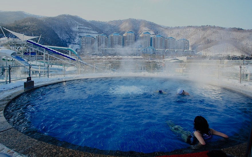 Thermal bath with swimmers at Vivaldi Park Ski World, snowy mountains in the background.