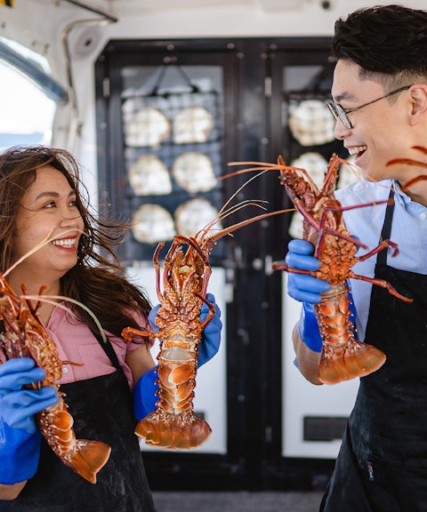 Guests holding lobsters on Rottnest Island Luxe Seafood Cruise.