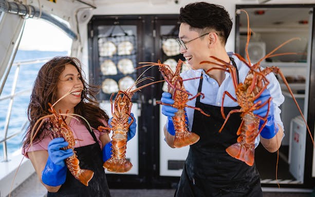 Guests holding lobsters on Rottnest Island Luxe Seafood Cruise.