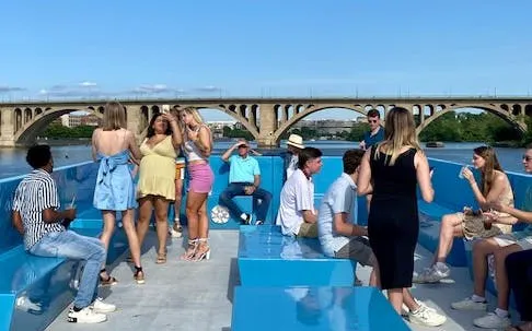 Boomerang DC brunch cruise with guests enjoying open bar and live DJ near city bridge.