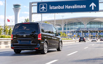 Private transfer van approaching Istanbul Airport terminal.