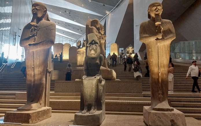 Statues inside the Grand Egyptian Museum with visitors exploring the exhibits.