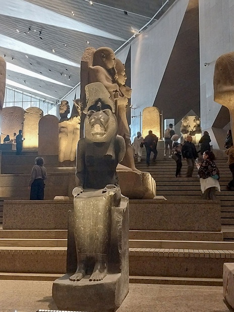 Statues inside the Grand Egyptian Museum with visitors exploring the exhibits.