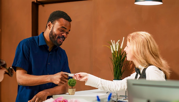 Guest receiving room card at Disneyland Hotel Paris reception desk.