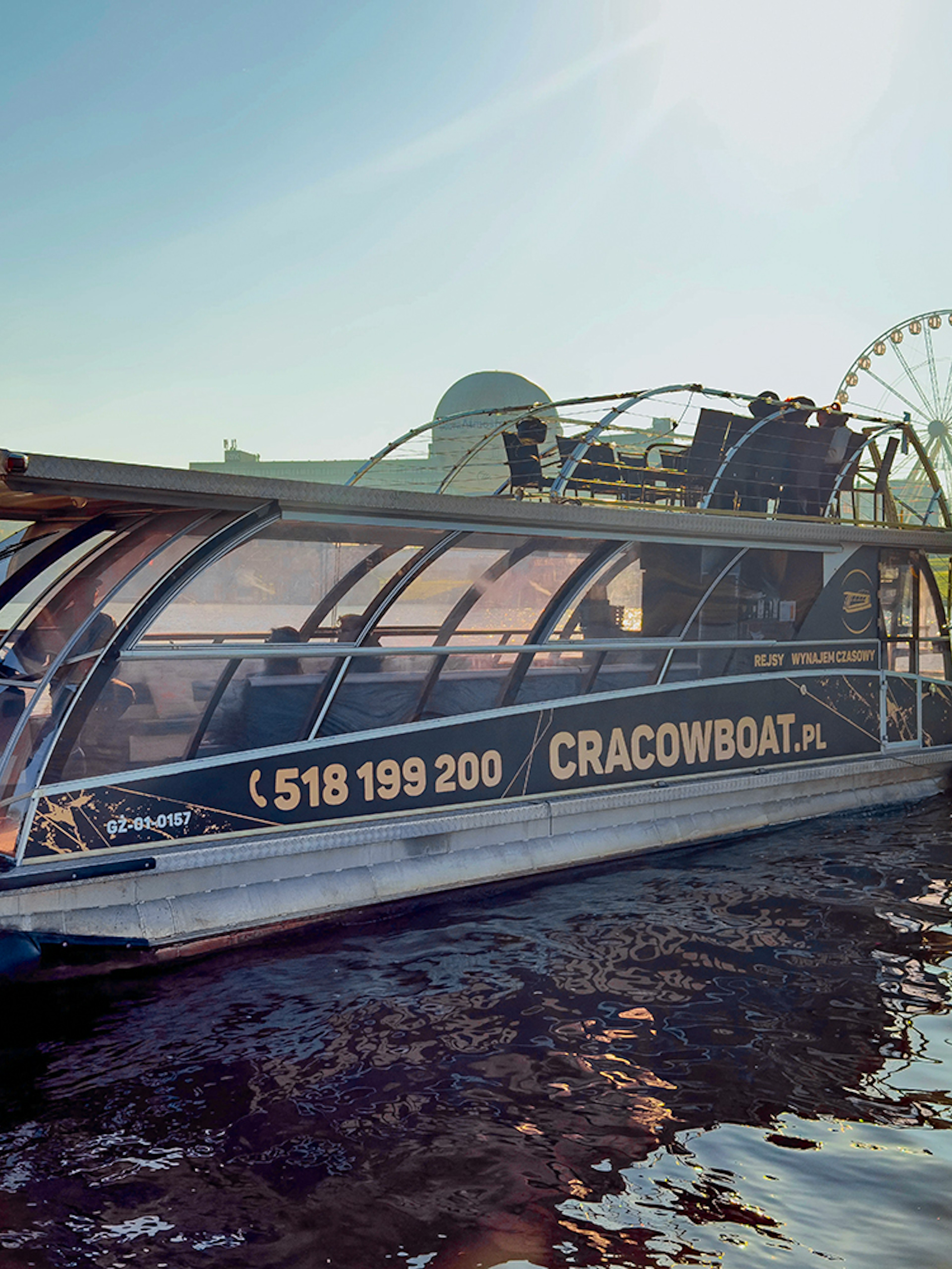 Vistula River cruise boat docked with ferris wheel in background, Krakow, Poland.