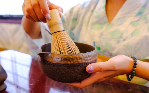 Person whisking matcha in a bowl during a Tokyo spring tea ceremony.
