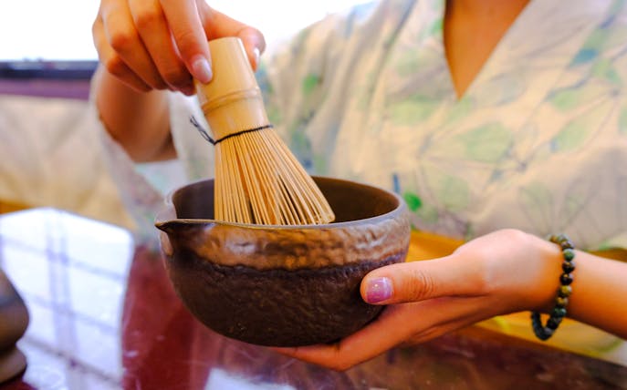 Person whisking matcha in a bowl during a Tokyo spring tea ceremony.