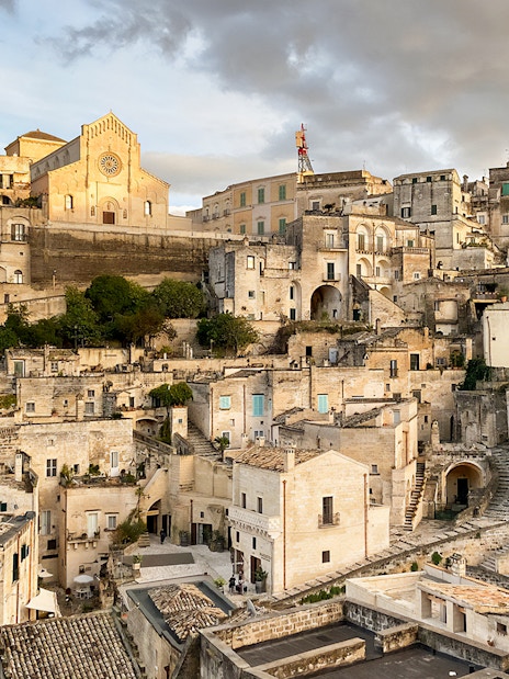 Matera's ancient stone buildings and church under a cloudy sky during a 2-hour guided tour.