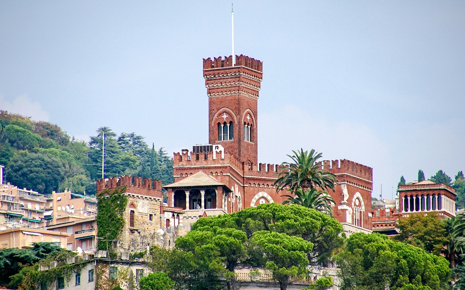 Castello d'Albertis in Genoa surrounded by lush greenery and historic architecture.