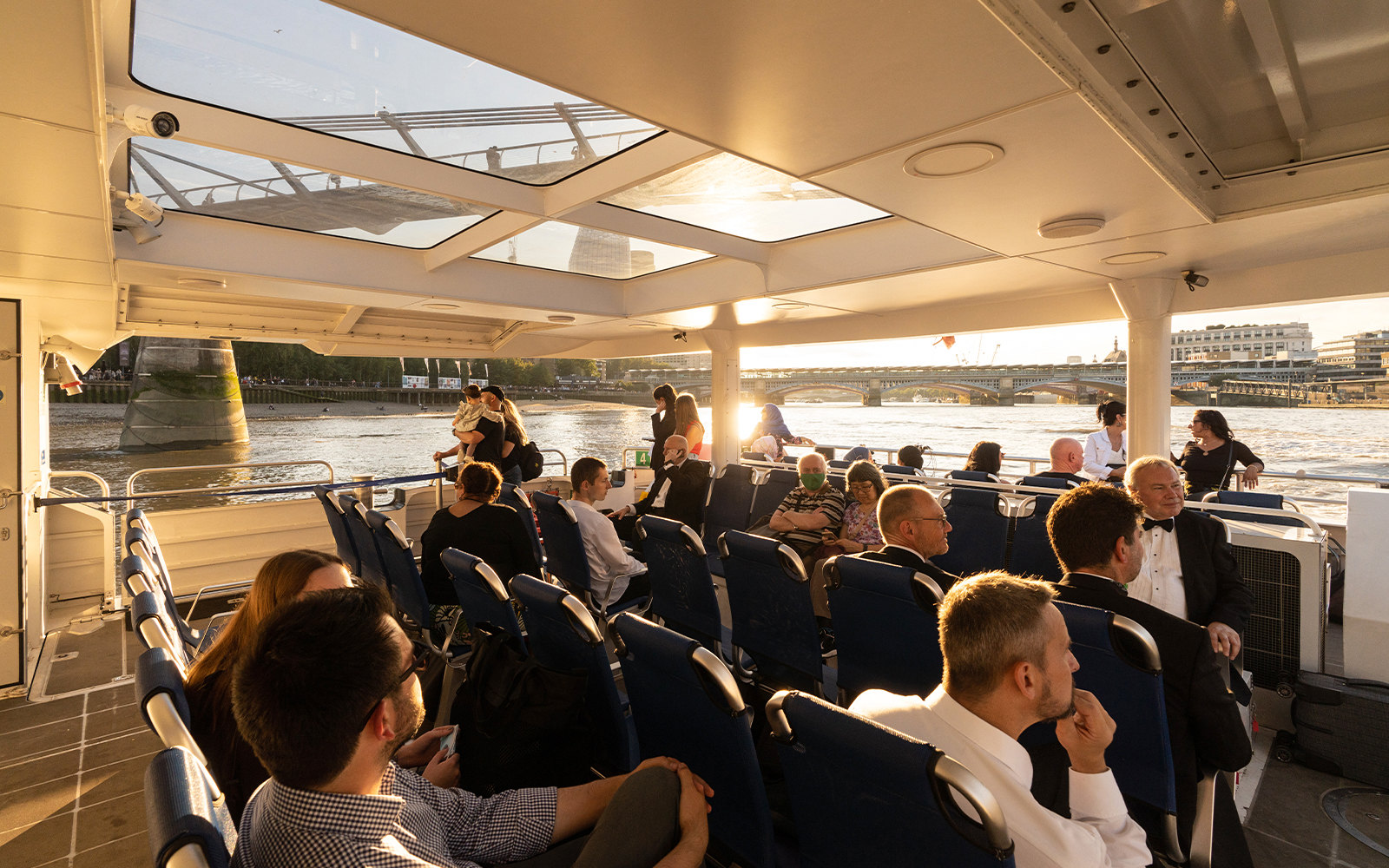 Passengers enjoying a ride on the Thames River Uber Boat with views of London bridges.
