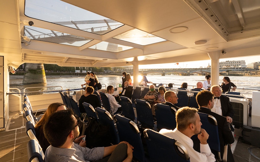 Passengers enjoying a ride on the Thames River Uber Boat with views of London bridges.