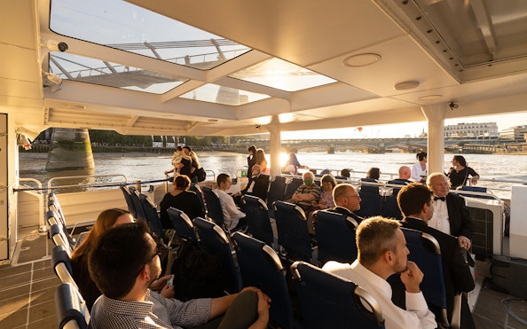 Passengers enjoying a ride on the Thames River Uber Boat with views of London bridges.