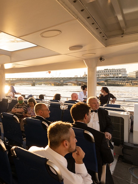 Passengers enjoying a ride on the Thames River Uber Boat with views of London bridges.