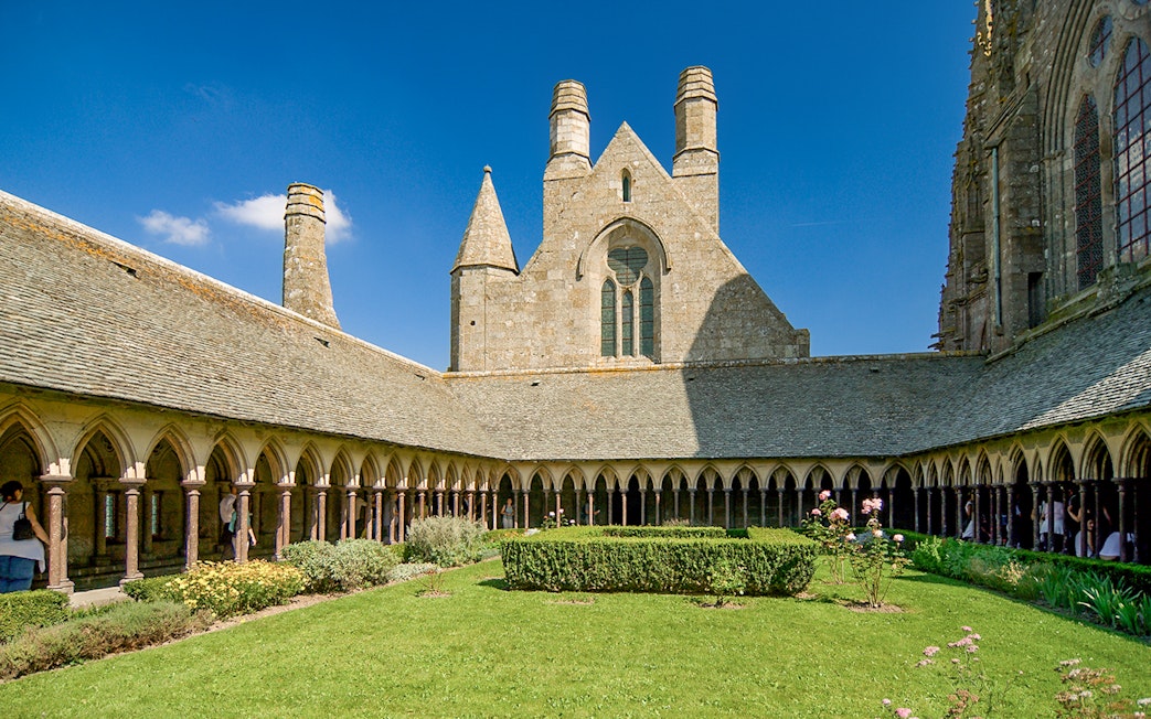 Mont St. Michel Abbey cloister with tourists on a full-day tour from Paris.