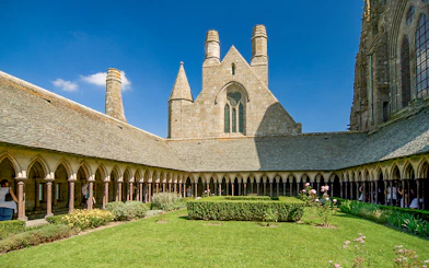 Mont St. Michel Abbey cloister with tourists on a full-day tour from Paris.