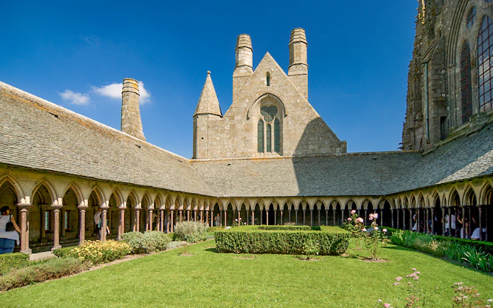 Mont St. Michel Abbey cloister with tourists on a full-day tour from Paris.