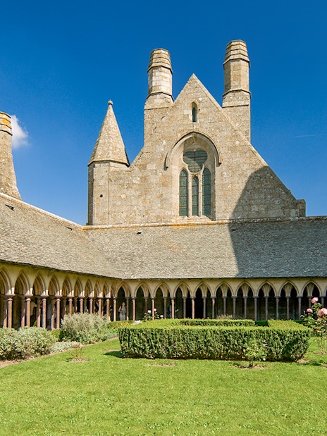 Mont St. Michel Abbey cloister with tourists on a full-day tour from Paris.