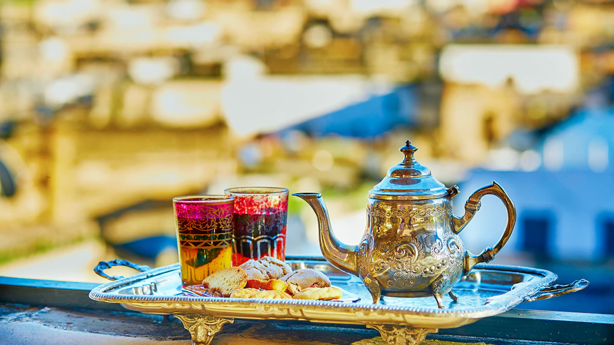 Silver teapot and glasses with pastries on a tray