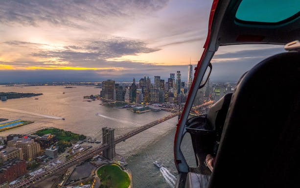 Helicopter view of NYC skyline and Brooklyn Bridge at sunset from Linden Airport tour.