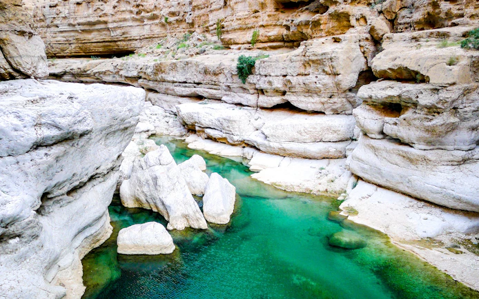 Turquoise waters flowing through rocky canyon at Wadi Shab near Muscat, Oman.