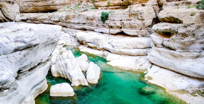 Turquoise waters flowing through rocky canyon at Wadi Shab near Muscat, Oman.