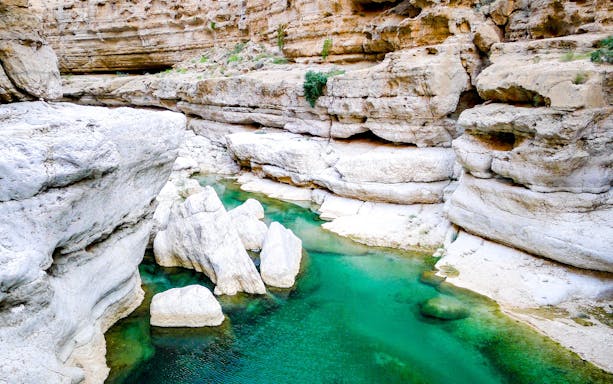 Turquoise waters flowing through rocky canyon at Wadi Shab near Muscat, Oman.