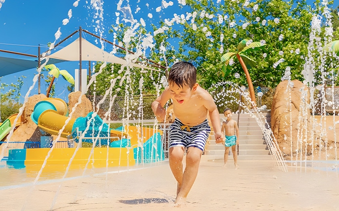 Child playing in water jets at Aquopolis Villanueva de la Cañada Tiki Island.