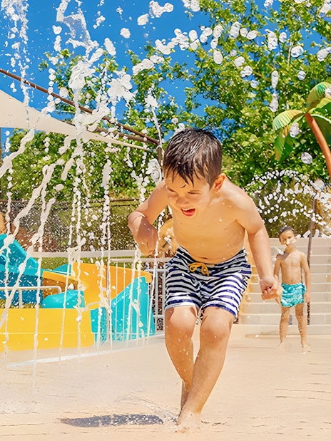 Child playing in water jets at Aquopolis Villanueva de la Cañada Tiki Island.