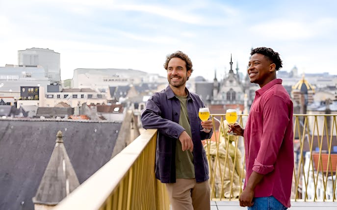 Visitors enjoying beer on a museum balcony with cityscape views.