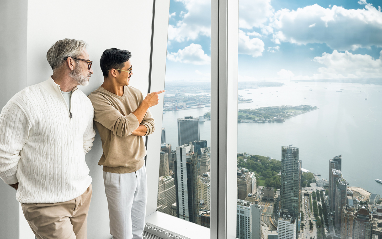 Tourists enjoying the view from One World Observatory, overlooking New York City and the Hudson River.