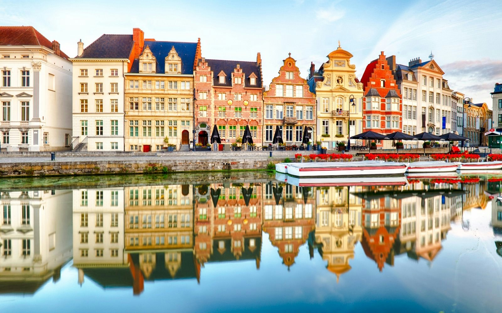 Graslei and Korenlei quays along the Leie river in Ghent, Belgium, with historic buildings reflected in the water.
