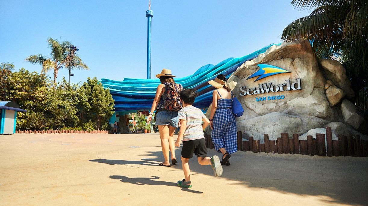 Visitors entering SeaWorld San Diego under a blue wave-themed entrance.
