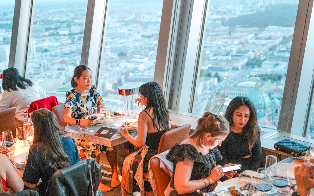 Guests dining at the Berlin TV Tower restaurant with city views.